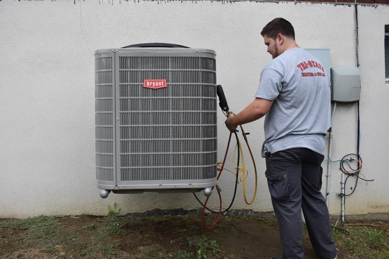 Technician in Tri-State shirt servicing outdoor air conditioning unit